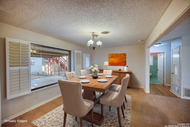 tiled dining area featuring a notable chandelier and a textured ceiling