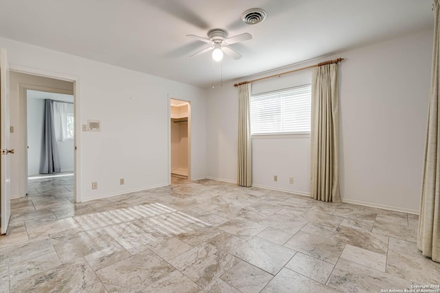 unfurnished bedroom with ceiling fan, a spacious closet, and multiple windows