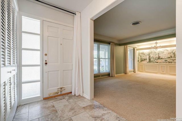 foyer featuring light colored carpet and an inviting chandelier