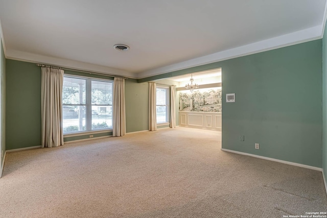 spare room featuring carpet and an inviting chandelier