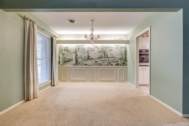 empty room featuring carpet and a chandelier