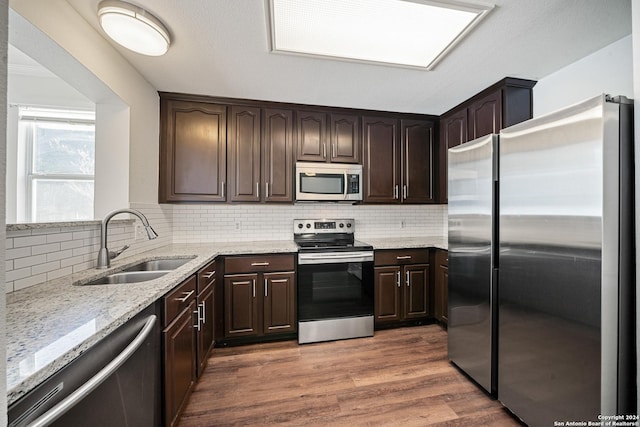 kitchen featuring backsplash, dark wood-type flooring, sink, dark brown cabinetry, and stainless steel appliances