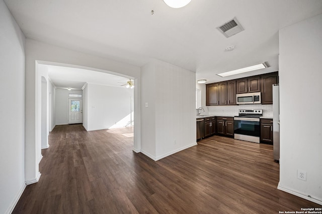 kitchen featuring dark wood-type flooring, ceiling fan, decorative backsplash, appliances with stainless steel finishes, and dark brown cabinets