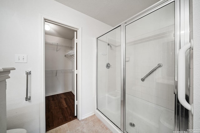 bathroom with tile patterned floors, a shower with shower door, and a textured ceiling