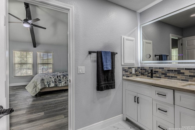 bathroom featuring backsplash, vanity, ceiling fan, wood-type flooring, and beam ceiling