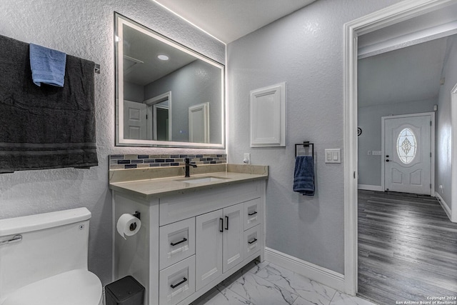 bathroom with vanity, hardwood / wood-style flooring, toilet, and tasteful backsplash