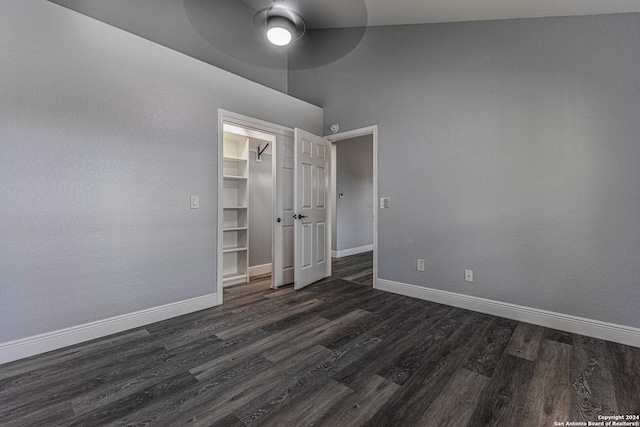 unfurnished bedroom with ceiling fan, high vaulted ceiling, dark hardwood / wood-style floors, a walk in closet, and a closet