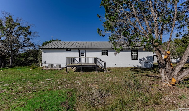 rear view of house with a deck, central AC unit, and a lawn