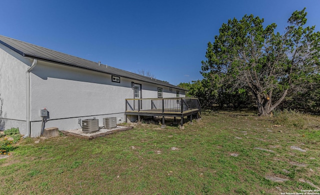 rear view of property with a lawn, central air condition unit, and a deck