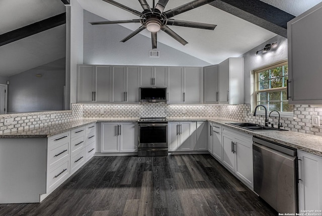 kitchen featuring sink, vaulted ceiling with beams, appliances with stainless steel finishes, tasteful backsplash, and dark hardwood / wood-style flooring