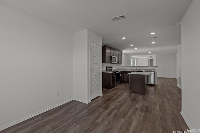 kitchen featuring dark wood-type flooring, appliances with stainless steel finishes, dark brown cabinets, a kitchen island, and a breakfast bar area