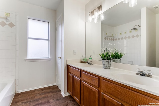 bathroom featuring hardwood / wood-style flooring, vanity, and tiled shower / bath combo