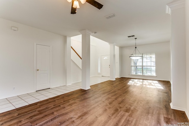 unfurnished living room with decorative columns, ceiling fan, and light wood-type flooring