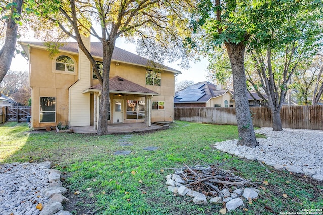 rear view of property with a lawn, ceiling fan, a patio area, and an outdoor fire pit