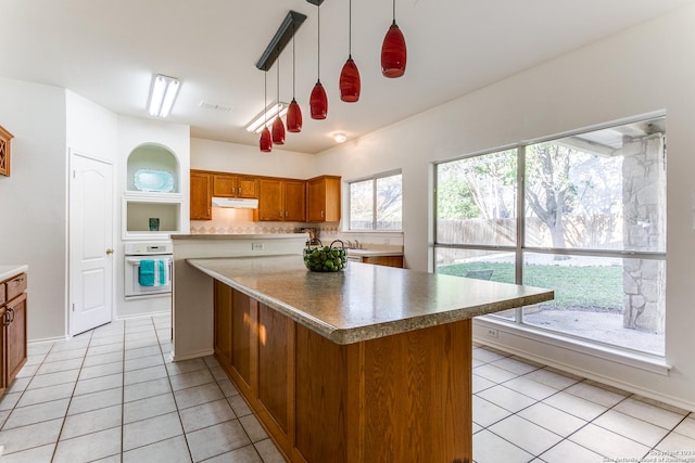 kitchen featuring a center island, oven, hanging light fixtures, and light tile patterned floors