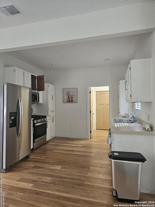 kitchen with white cabinetry, sink, wood-type flooring, and stainless steel appliances