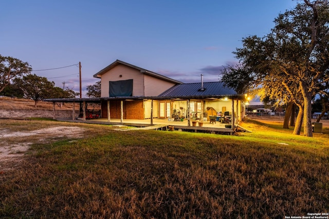 back house at dusk with a lawn