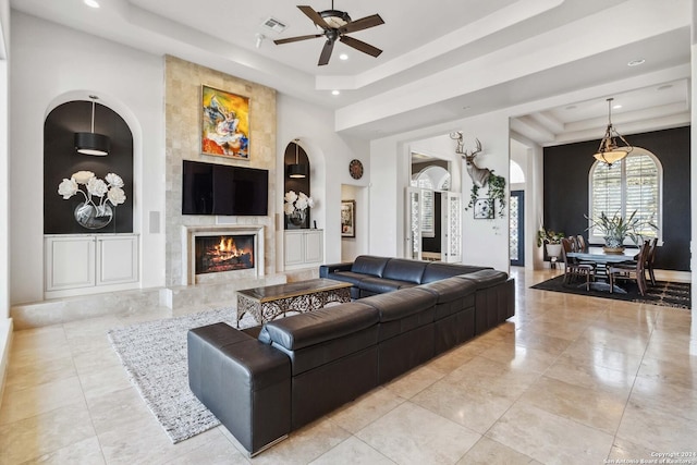 living room with built in features, a high end fireplace, a raised ceiling, and recessed lighting