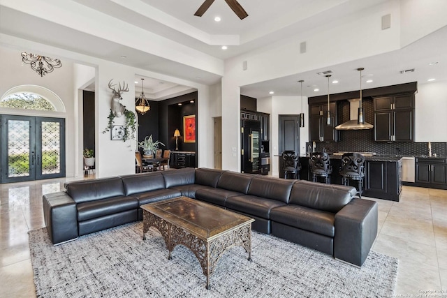 living room featuring light tile patterned floors, a ceiling fan, a tray ceiling, french doors, and recessed lighting