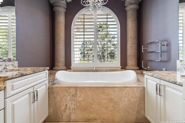 full bathroom featuring a wealth of natural light, two vanities, and ornate columns