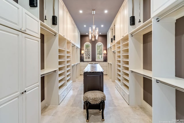 walk in closet with a notable chandelier and light tile patterned floors