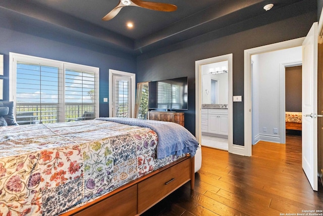 bedroom with ceiling fan, connected bathroom, baseboards, dark wood-style floors, and a raised ceiling