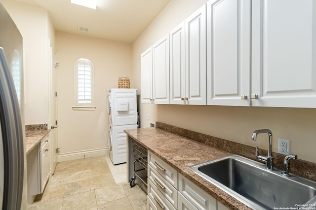 kitchen featuring a sink, visible vents, white cabinetry, baseboards, and stainless steel fridge