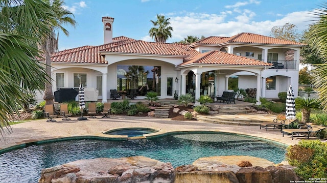 rear view of house with a tiled roof, a patio area, a balcony, and stucco siding