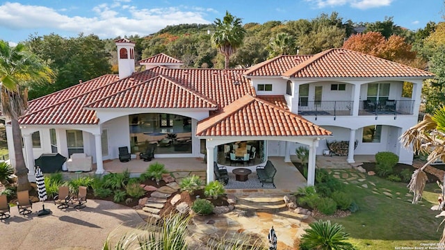 back of property with a patio, a tile roof, a balcony, and stucco siding