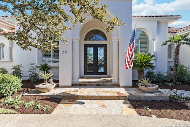 property entrance featuring french doors, a tile roof, and stucco siding