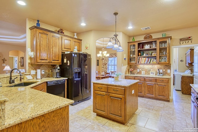 kitchen with sink, decorative light fixtures, kitchen peninsula, light stone countertops, and black appliances