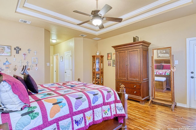 bedroom featuring a raised ceiling, crown molding, ceiling fan, and light hardwood / wood-style flooring