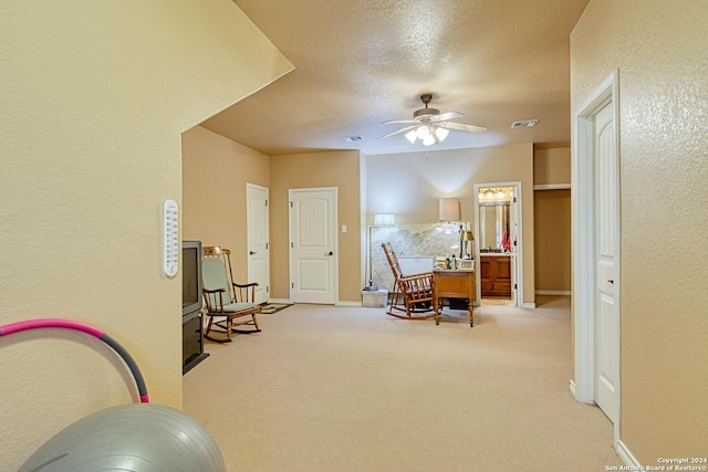 sitting room featuring ceiling fan, light carpet, and a textured ceiling