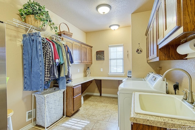 washroom with sink, cabinets, washer and clothes dryer, light tile patterned floors, and a textured ceiling