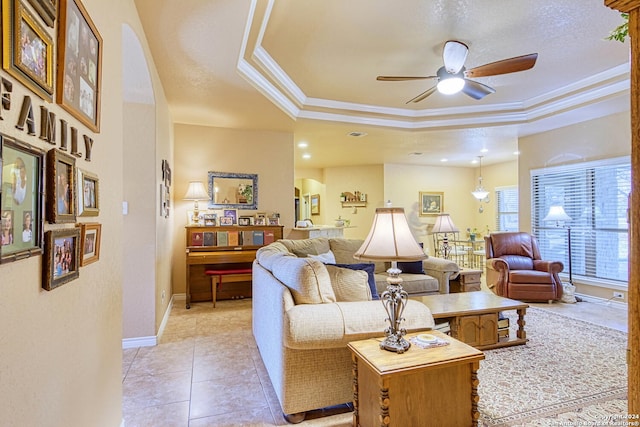 living room with crown molding, a textured ceiling, light tile patterned floors, a tray ceiling, and ceiling fan