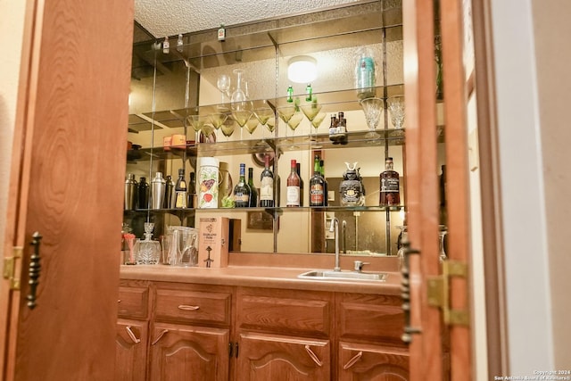 bar with sink and a textured ceiling