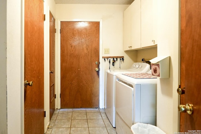 laundry room featuring cabinets, a textured ceiling, separate washer and dryer, and light tile patterned flooring