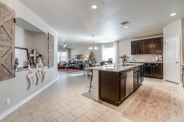 kitchen featuring dishwasher, ceiling fan with notable chandelier, sink, an island with sink, and dark brown cabinets