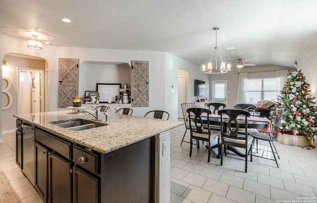 kitchen with ceiling fan with notable chandelier, sink, hanging light fixtures, lofted ceiling, and an island with sink