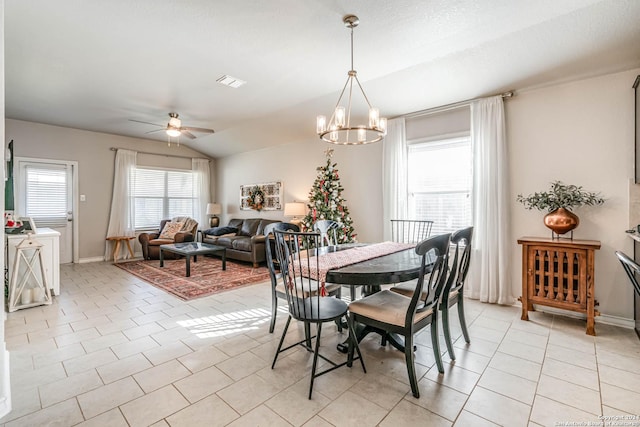 tiled dining area featuring ceiling fan with notable chandelier and lofted ceiling