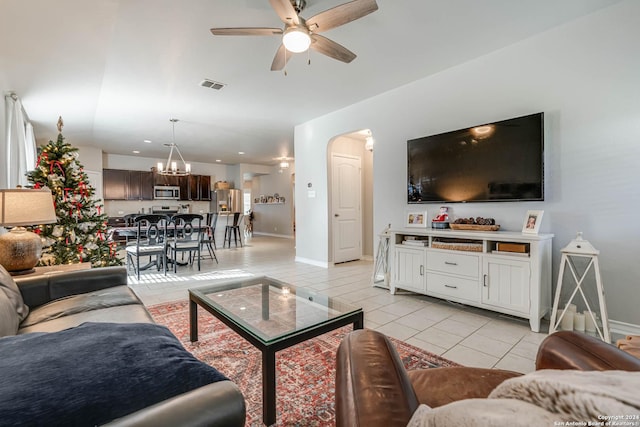 tiled living room with ceiling fan with notable chandelier