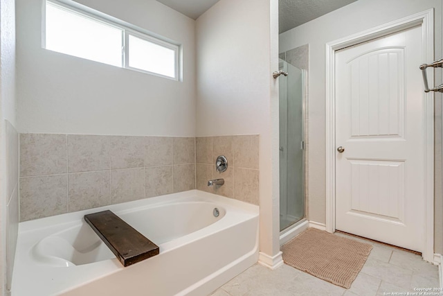 bathroom featuring tile patterned flooring, shower with separate bathtub, and a textured ceiling