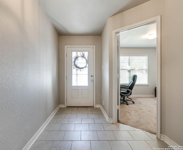 doorway with light tile patterned floors and a wealth of natural light