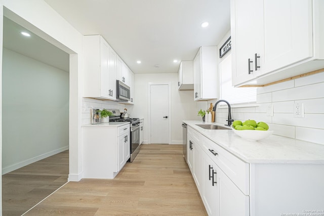 kitchen with sink, white cabinets, stainless steel appliances, and light hardwood / wood-style flooring