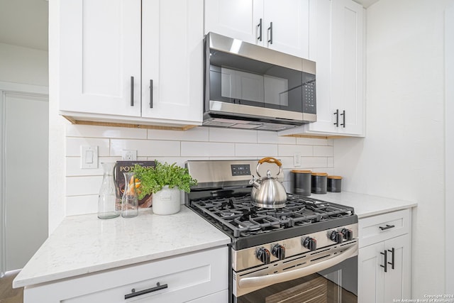 kitchen featuring tasteful backsplash, light stone counters, white cabinets, and stainless steel appliances