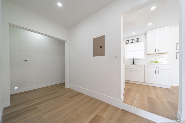 hallway with sink, electric panel, and light hardwood / wood-style flooring