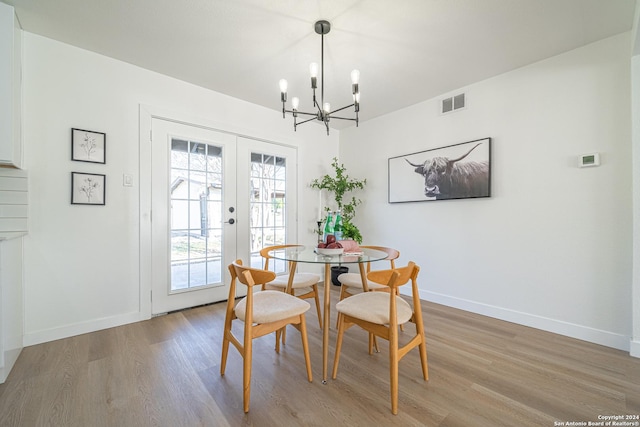 dining room with hardwood / wood-style floors, a chandelier, and french doors