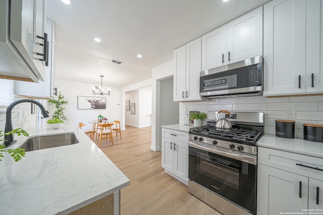 kitchen featuring white cabinetry, sink, appliances with stainless steel finishes, and light hardwood / wood-style flooring