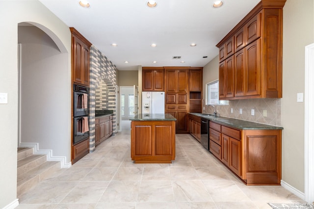 kitchen with backsplash, a center island, dark stone counters, and black appliances