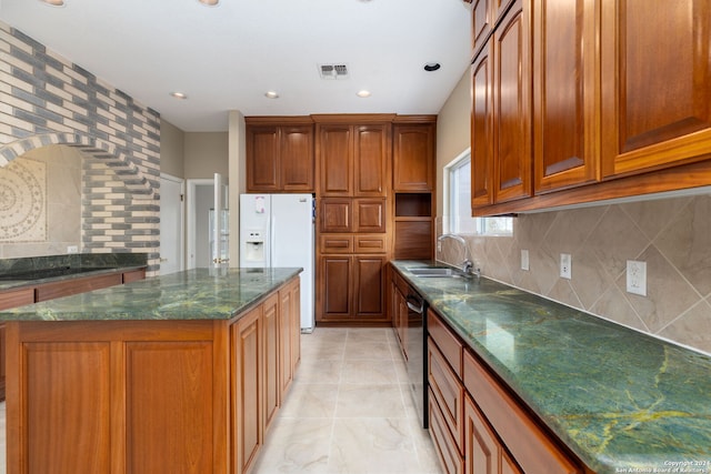 kitchen with dishwasher, sink, white refrigerator with ice dispenser, dark stone counters, and a kitchen island